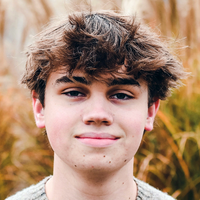 A student smiles while posing for a headshot in front of a white backdrop.