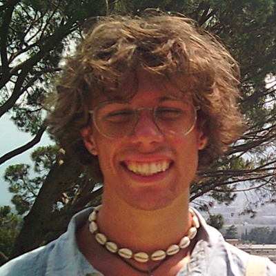 A student smiles while posing for a headshot outdoors.