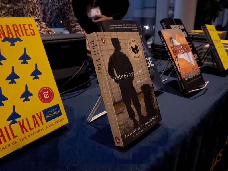 Display of books on stands on a table with a dark tablecloth, including 'Redeployment' and 'Missionaries' by Phil Klay