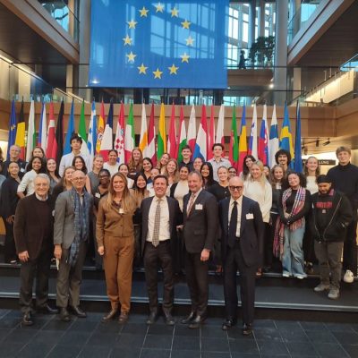 Syracuse Abroad students and advisors stand in font of flags at the European Council