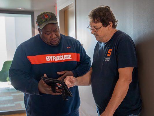 Two men in Syracuse shirts looking at an iPad