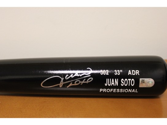 A black baseball bat signed by Juan Soto.