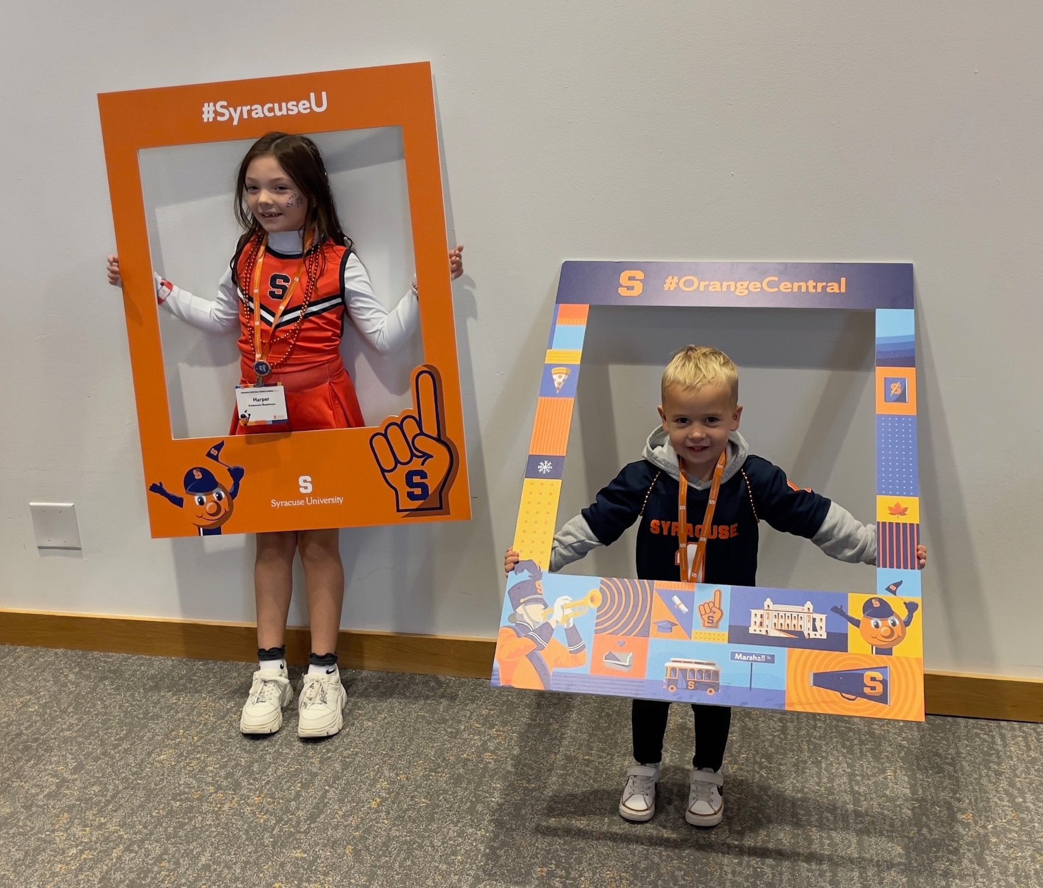 Two children holding Syracuse University branded photo frames - one in cheerleader uniform, one in Syracuse jacket