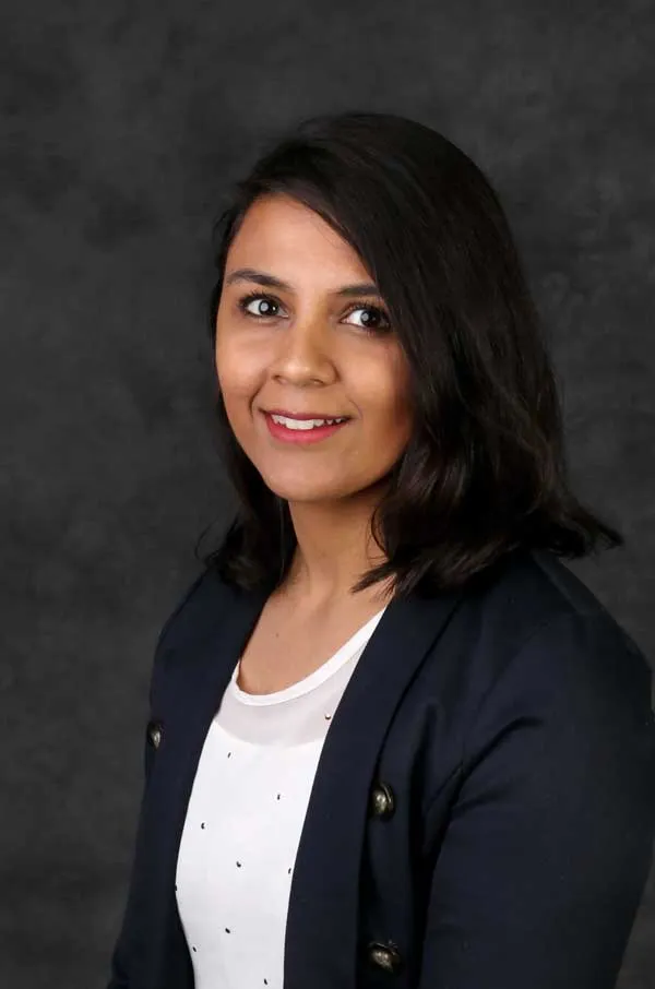 Person wearing black jacket and white shirt looking into the camera with a smile