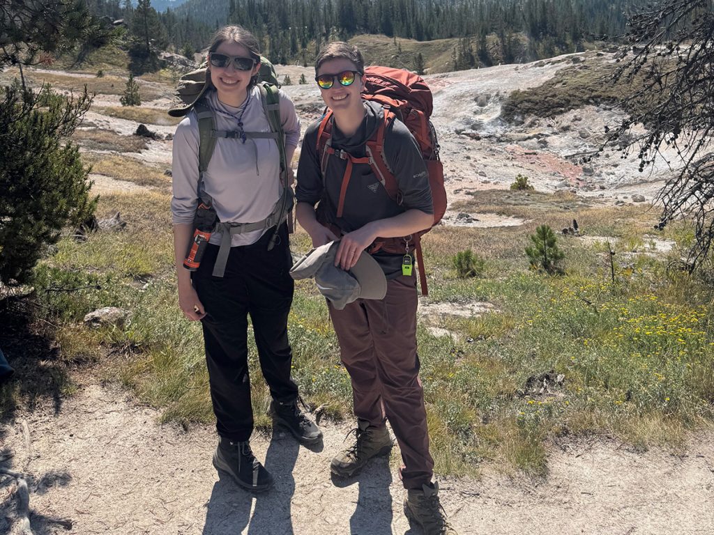Professor and student wearing sunglasses and backpacks on terrain