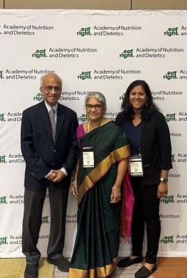 Three people standing in front of a white backdrop with repeated green and black text reading “Academy of Nutrition and Dietetics.”