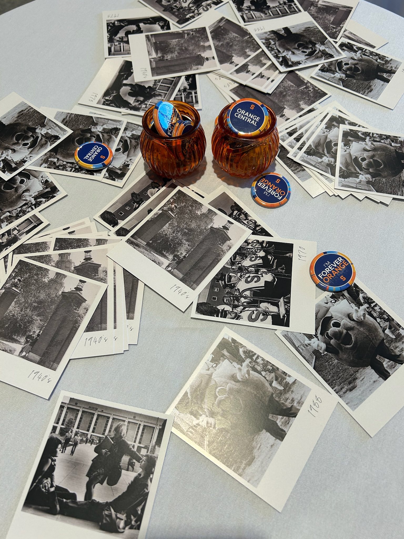 Vintage black-and-white Syracuse University photographs scattered around decorative votive candles with Orange Central branded tokens