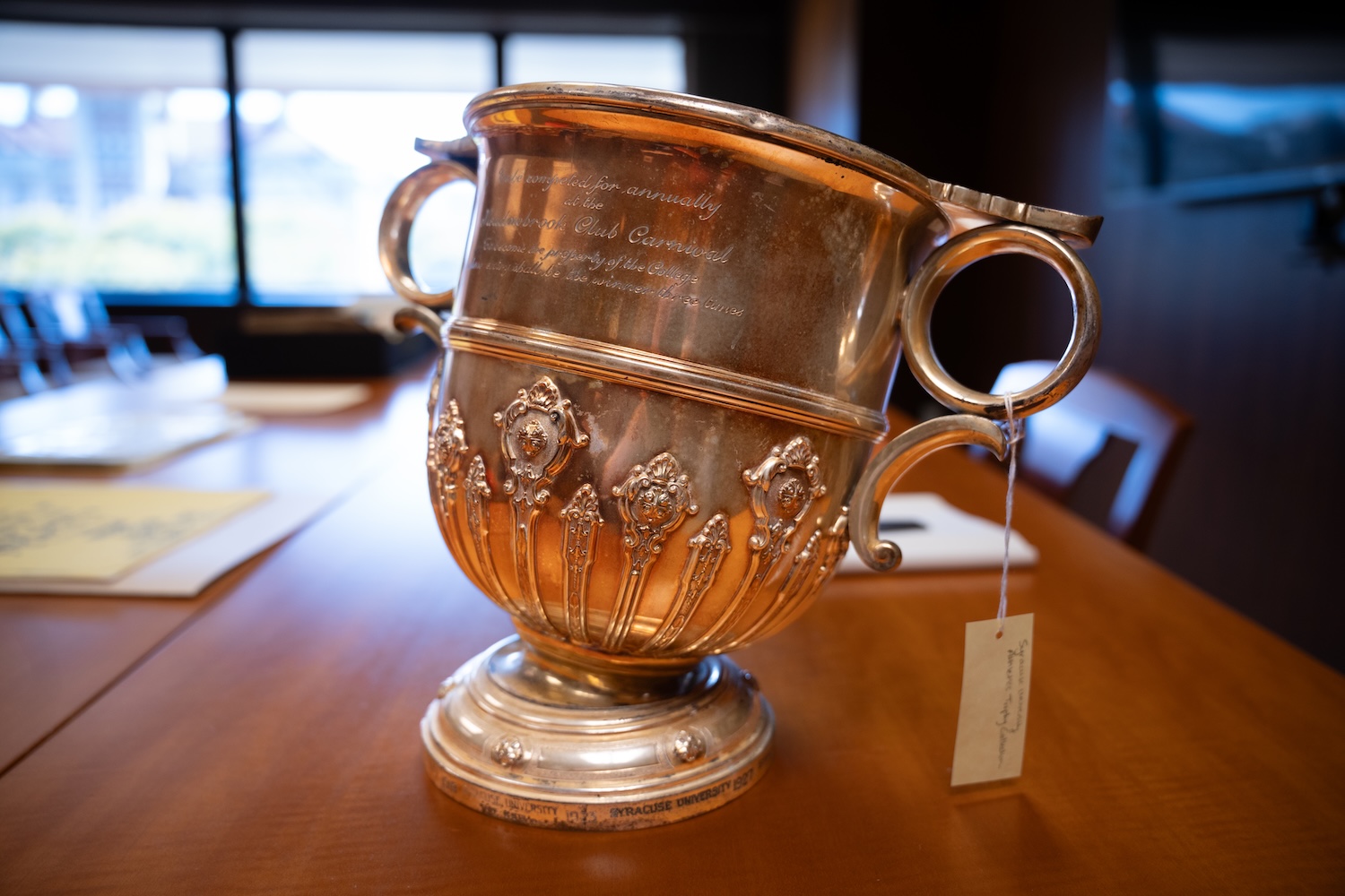 Tilted silver trophy with two handles on a wooden table