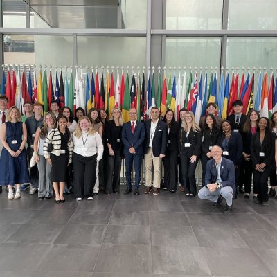 Group of professionals posing in front of international flags inside a modern building.