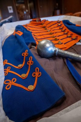 Blue and orange marching band uniform with gold accents and a silver mace.