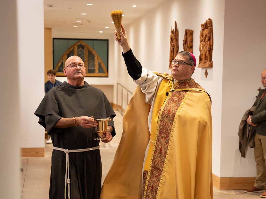 Bishop Douglas Lucia, assisted by Father Gerry Waterman, blesses the new Catholic Center