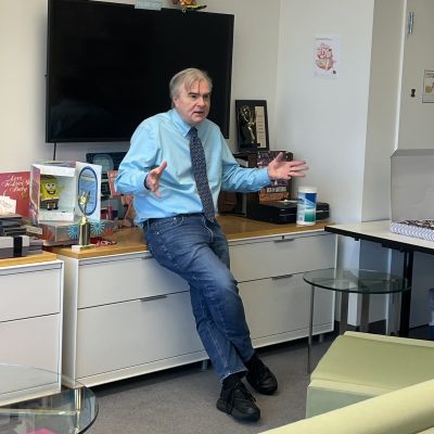Bob Thompson leaning on desk in front of class