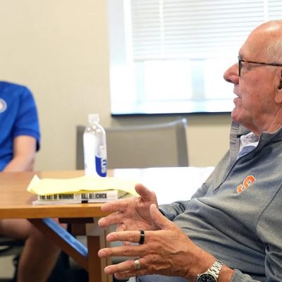 Two people seated in a classroom setting, engaged in conversation.