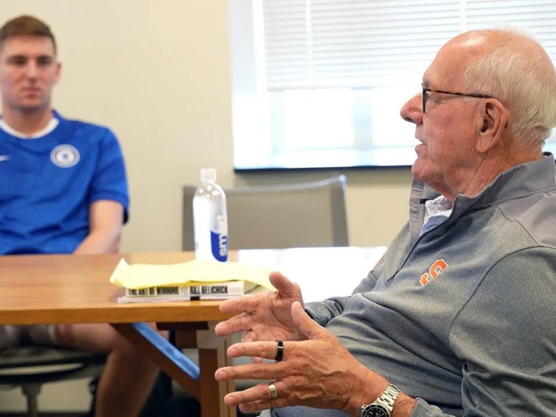 Two people seated in a classroom setting, engaged in conversation.