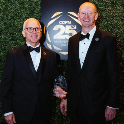 Two men in formal attire holding an award at the CDFM 25th Anniversary Gala.