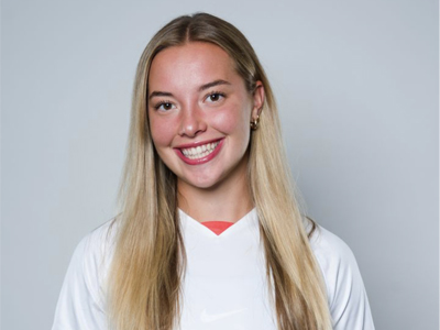 A person smiles while wearing a white Syracuse women's soccer jersey.