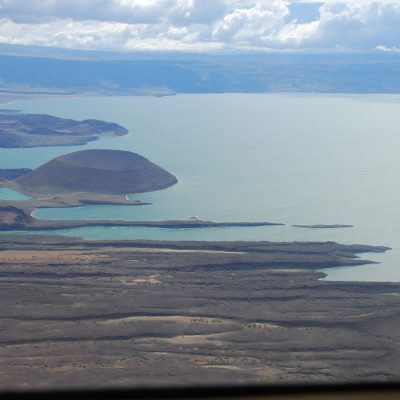 Aerial view of volcanic peninsulas extending into turquoise glacial waters.