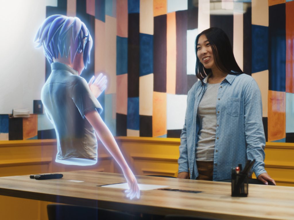 A person interacts with a holographic virtual influencer avatar displayed on a table.