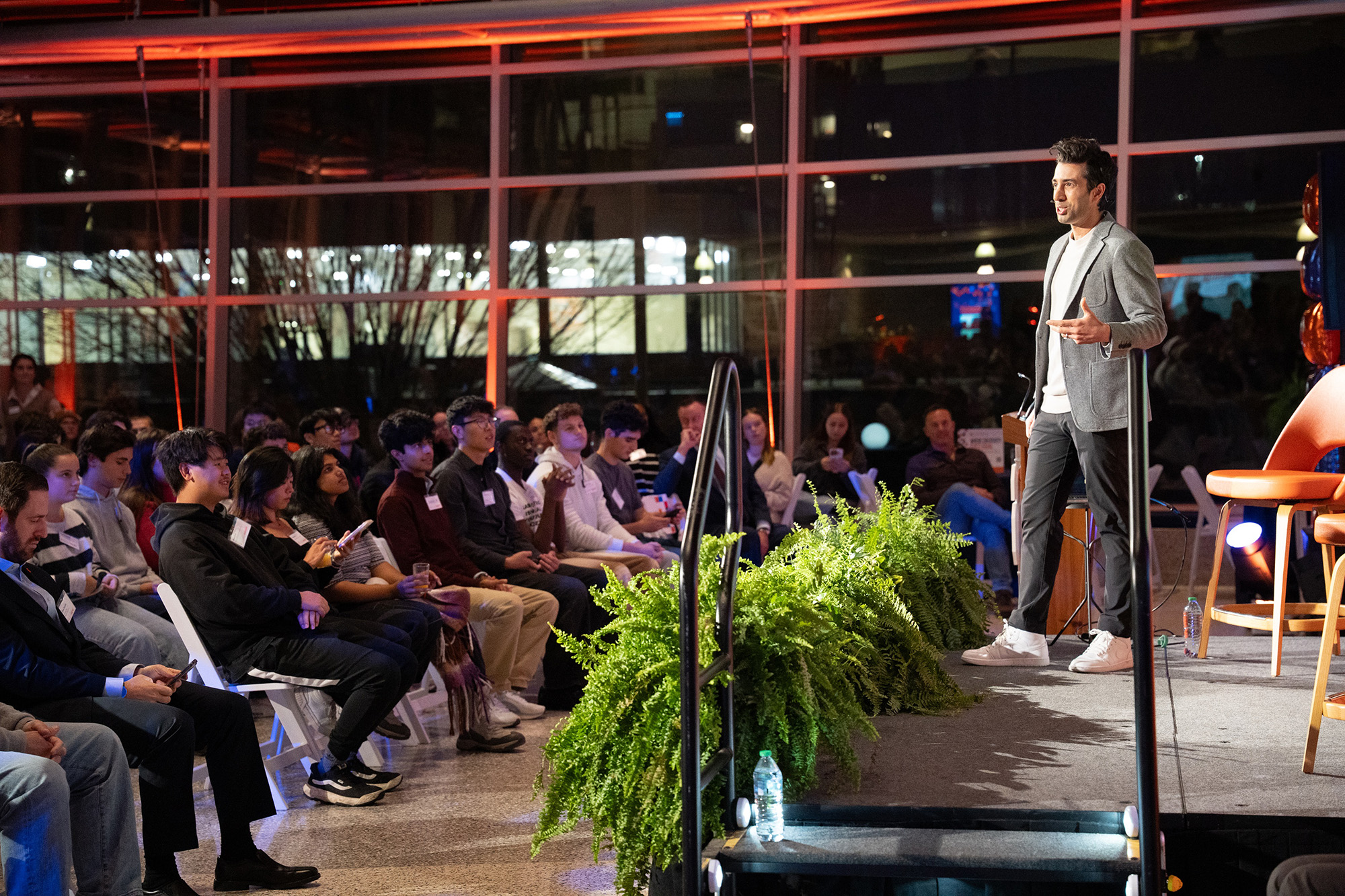 person on a stage presenting to a large group of people in a large room