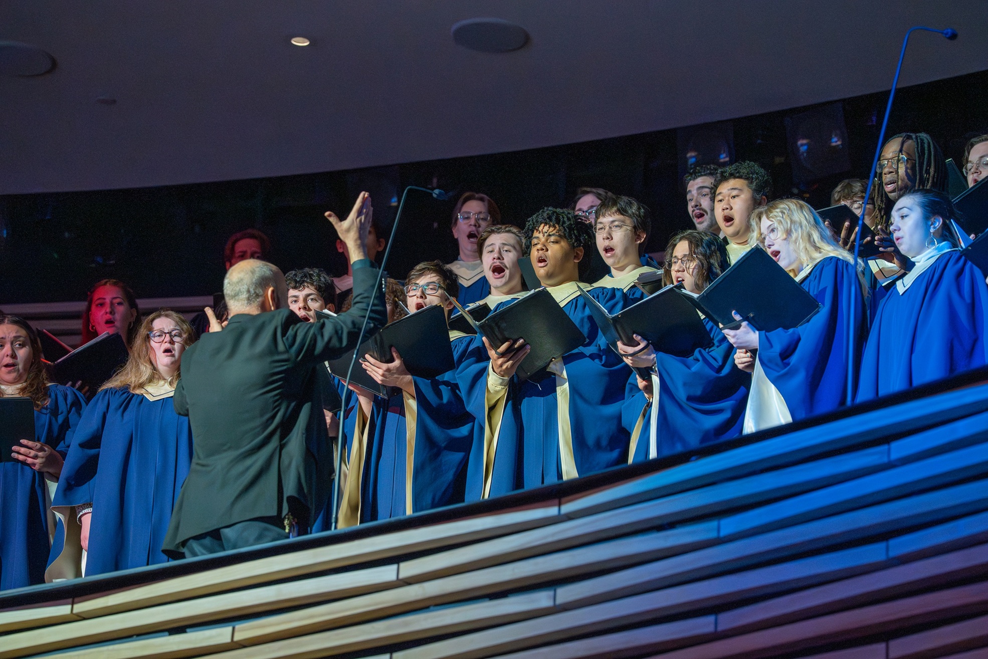 choir conductor leading a chorus dressed in robes