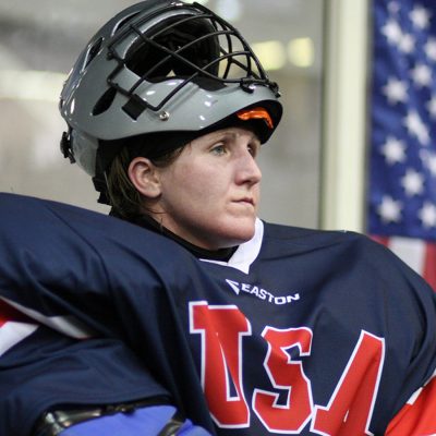 Woman in a hockey uniform and helmet