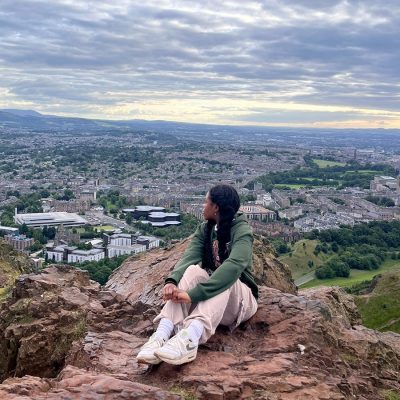 Woman sits on a rock overlooking a town