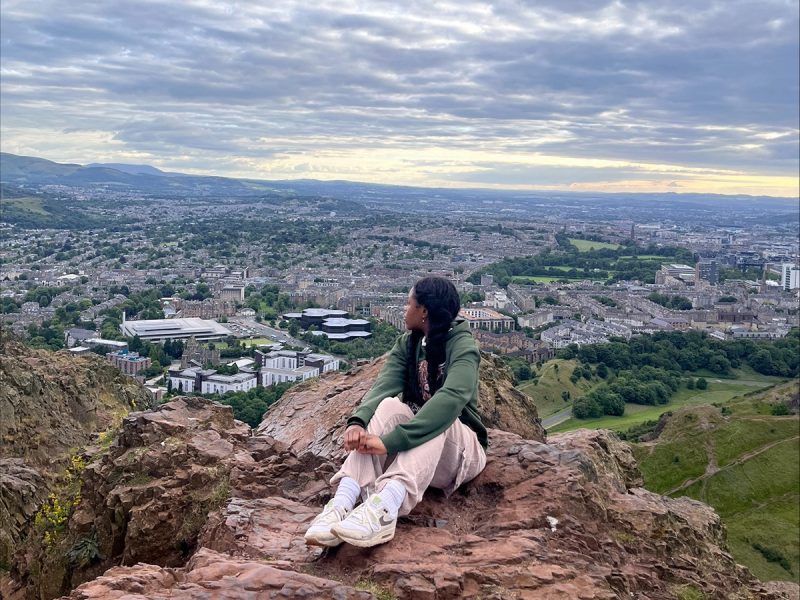 Woman sits on a rock overlooking a town