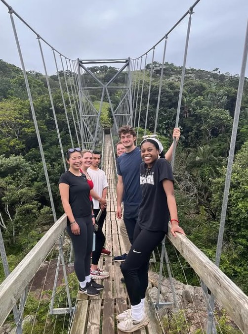 group of people standing on a rope bridge over a scenic landscape