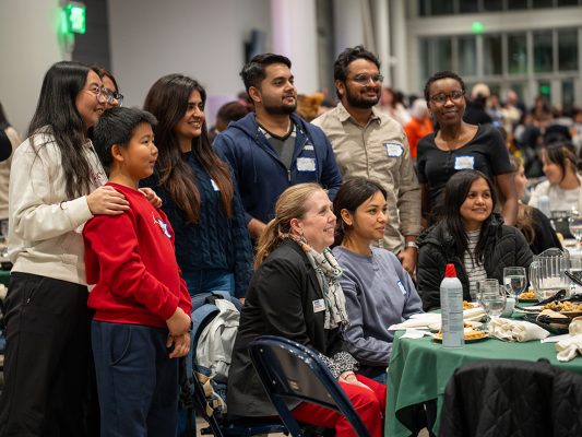People pose for a photo behind a table