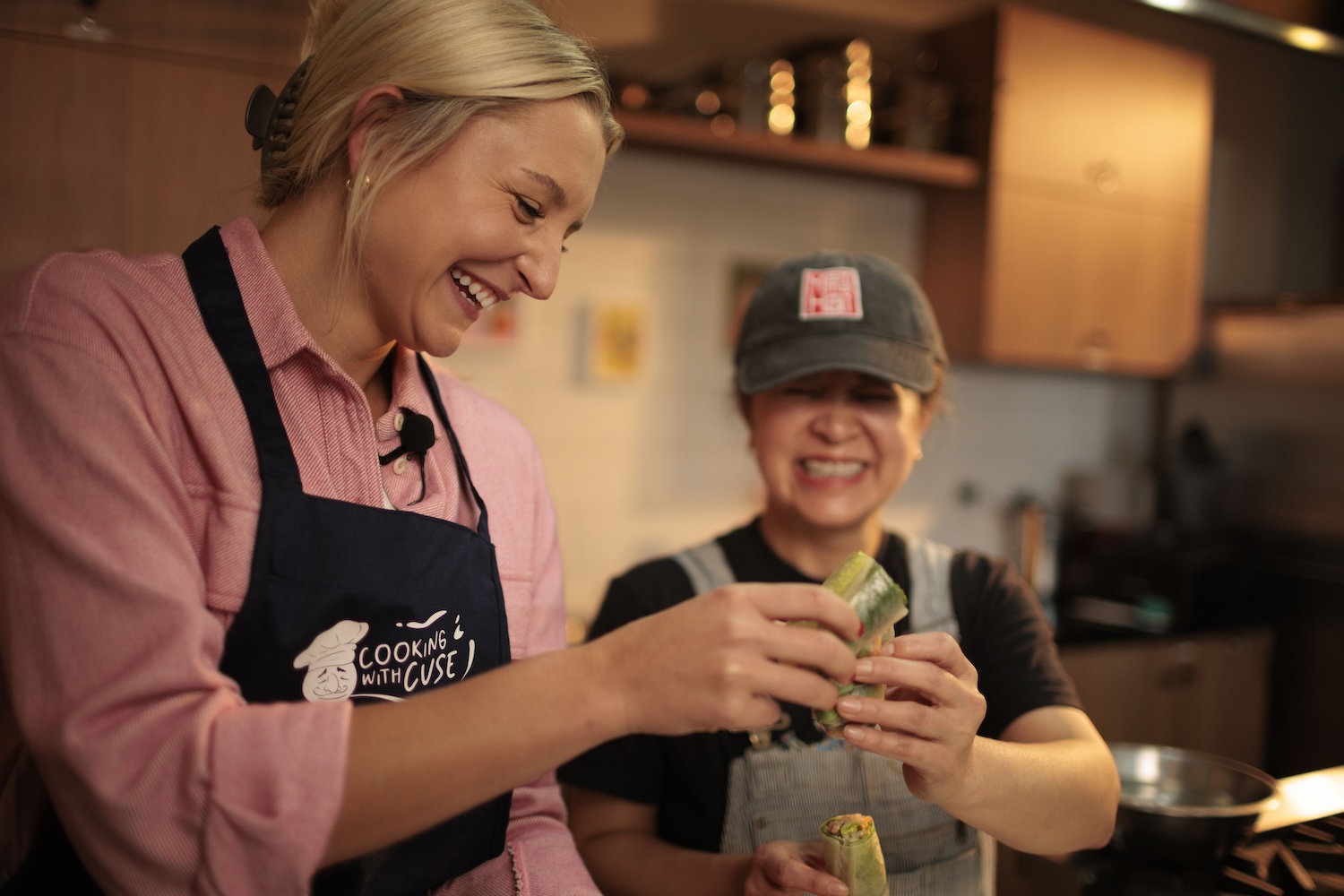 Two people stand smiling together at a kitchen counter