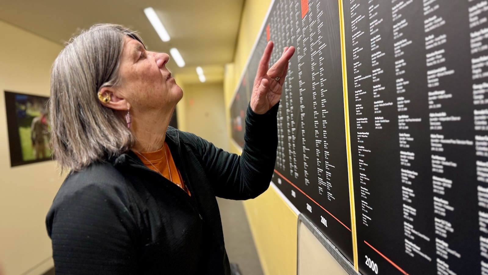 Person pointing at names on the memorial wall listing journalists killed.