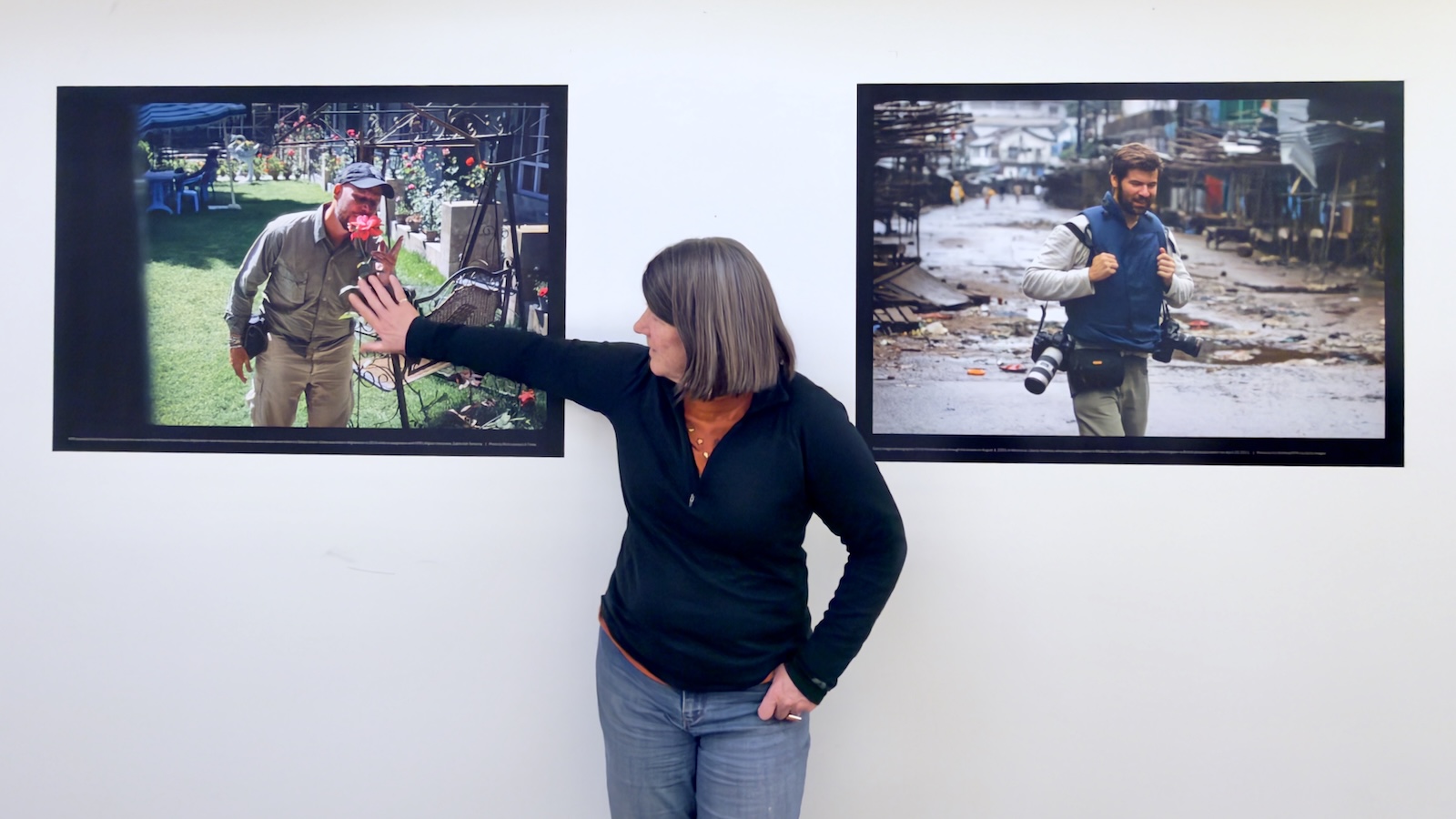 Person standing between two large photographs on a wall, with one hand extended toward the photo on the left showing an injured individual.