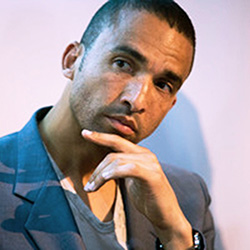 Man in grey jacket, with hand resting against his chin