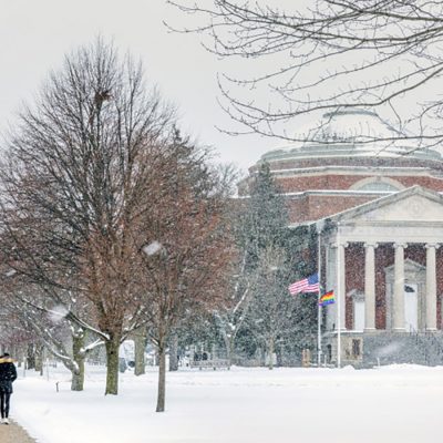 Exterior shot of Quad with Hendricks Chapel in snow, flags at half staff, students walking on sidewalk