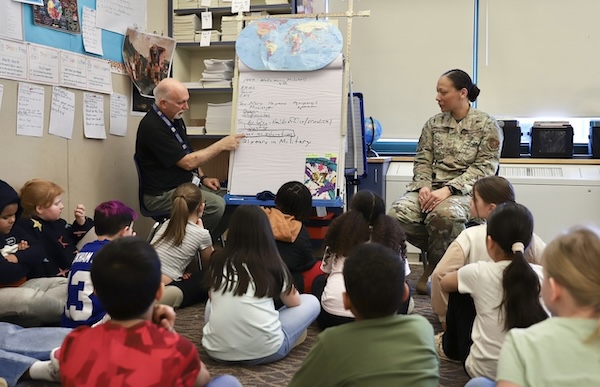 A National Guardswoman talks with a teacher and his class of middle-school students.