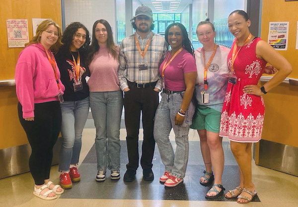 A group of student teachers pose together in a bright indoor environment
