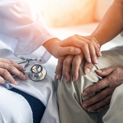 Healthcare professional holding a patient’s hand during a medical consultation