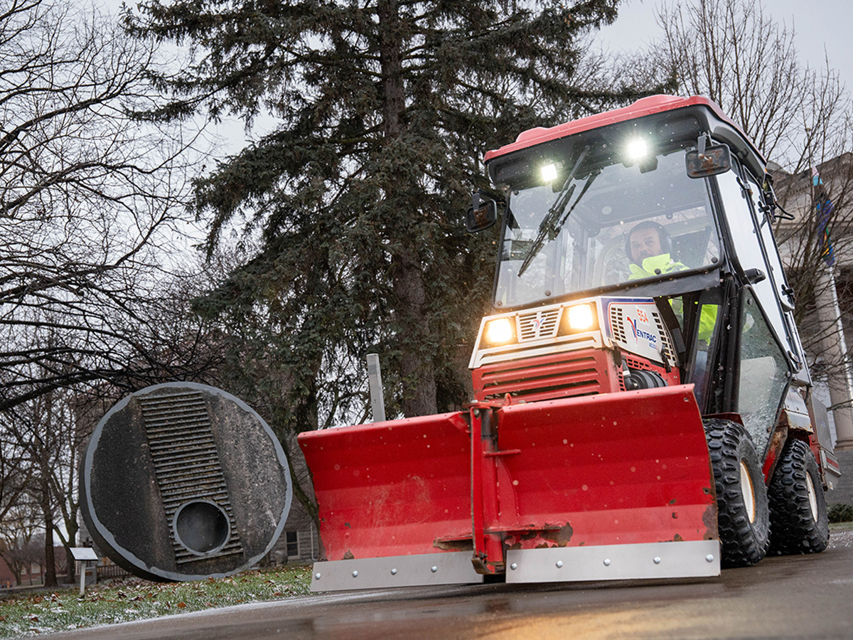A machine clears snow on the Kenneth A. Shaw Quad. Hendricks Chapel is in the background.
