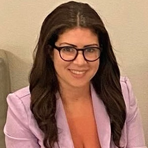 Woman in pink jacket and glasses, smiling