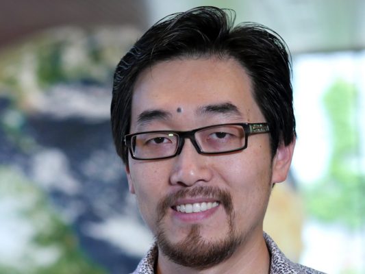 A person smiles while posing for a headshot outdoors.