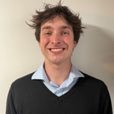 A person smiles while posing for a headshot indoors.