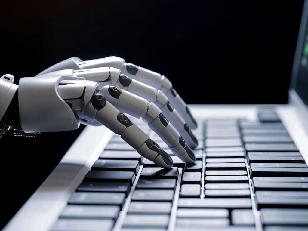 Robotic hand typing on computer keyboard.