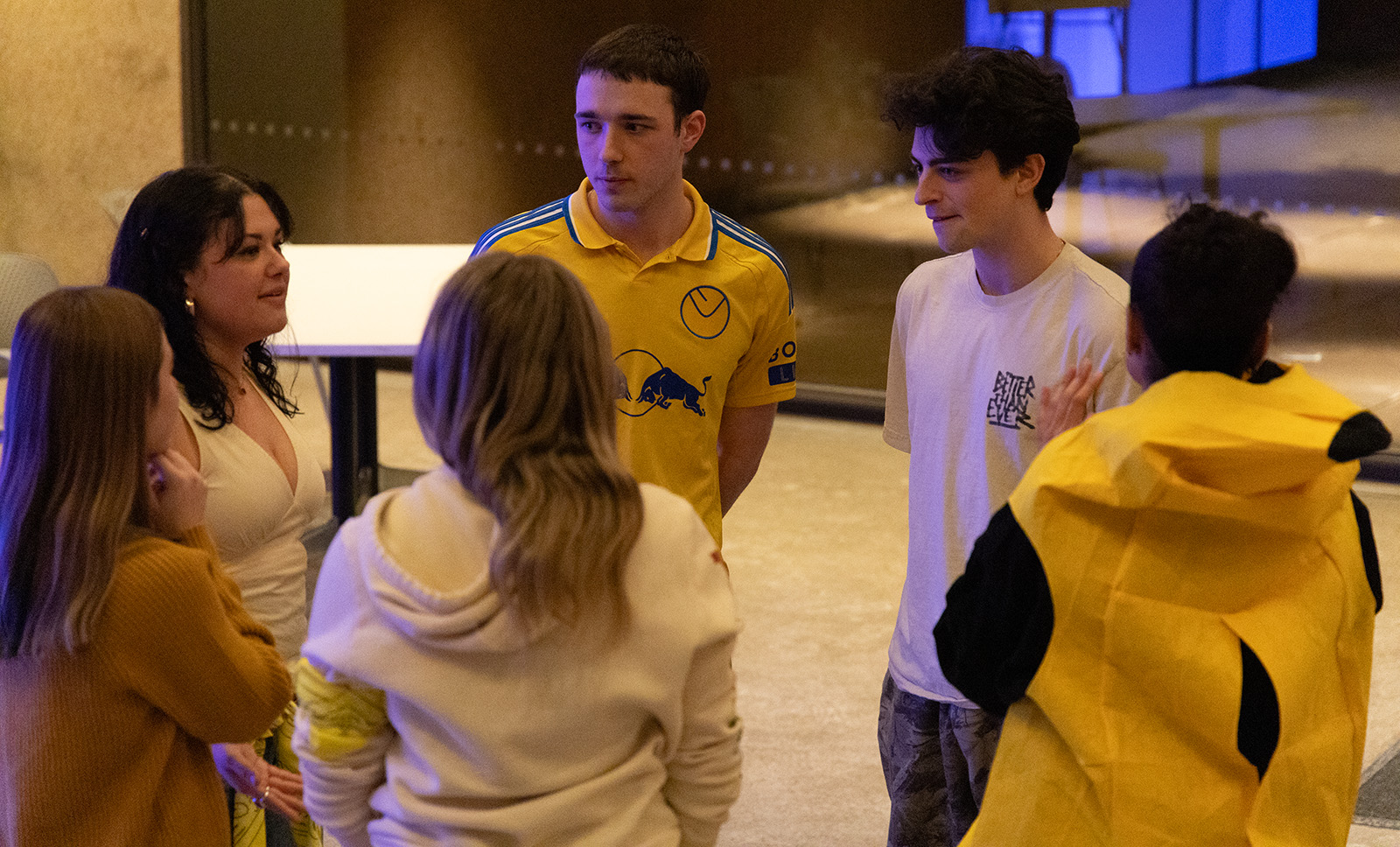 A small group of people standing in a circle indoors, engaged in lively conversation during an event