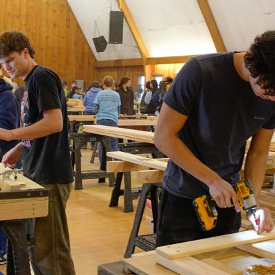 Students work on drilling and sanding bed frame materials