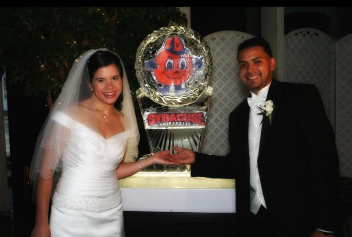 Bride and groom posing beside a sculpture featuring Otto the Orange mascot