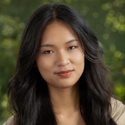 A person poses for a headshot while standing outside.