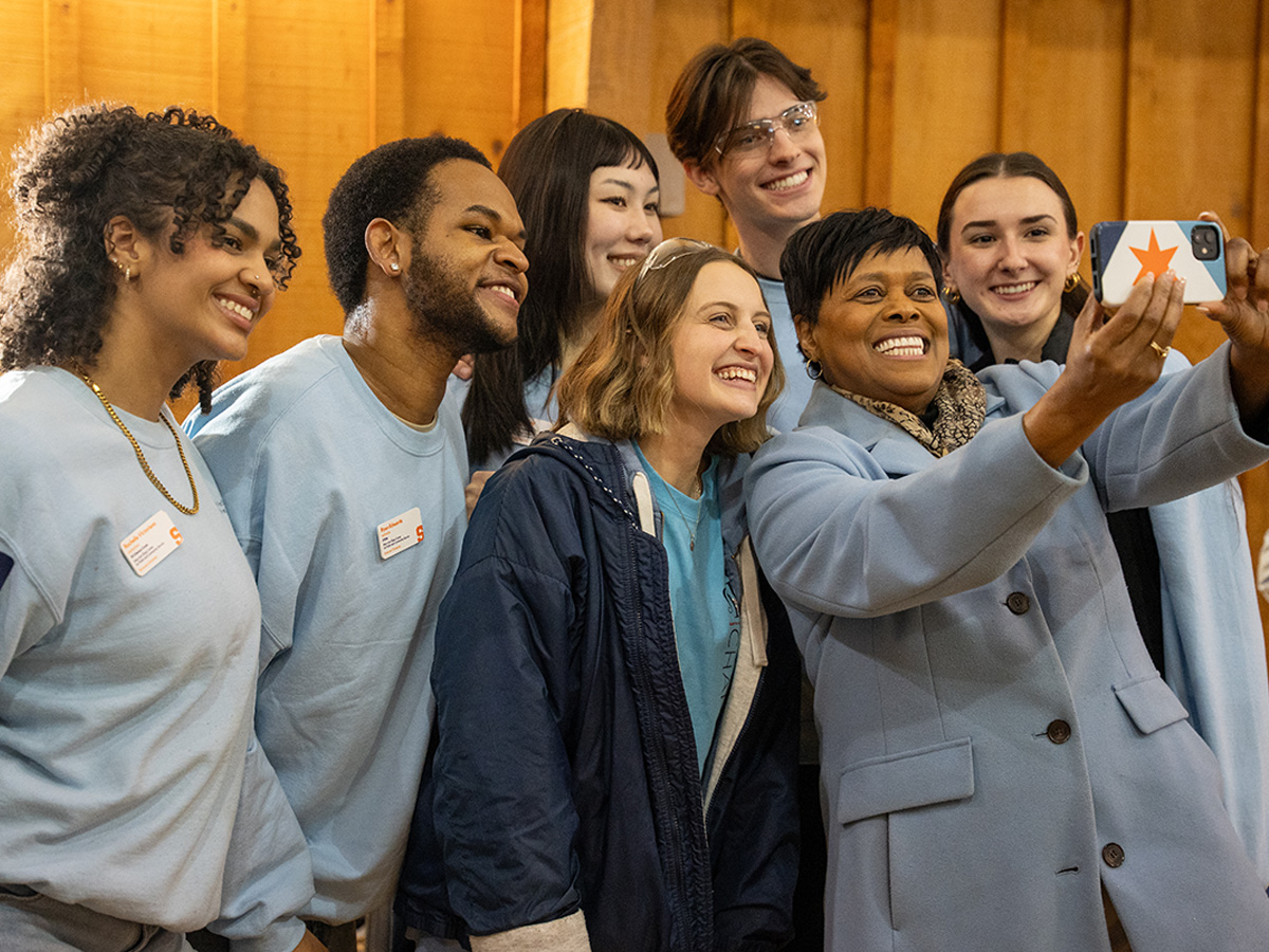 Student leaders, in blue t-shirts, pose for a selfie with Syracuse Mayor Sharon Owens.