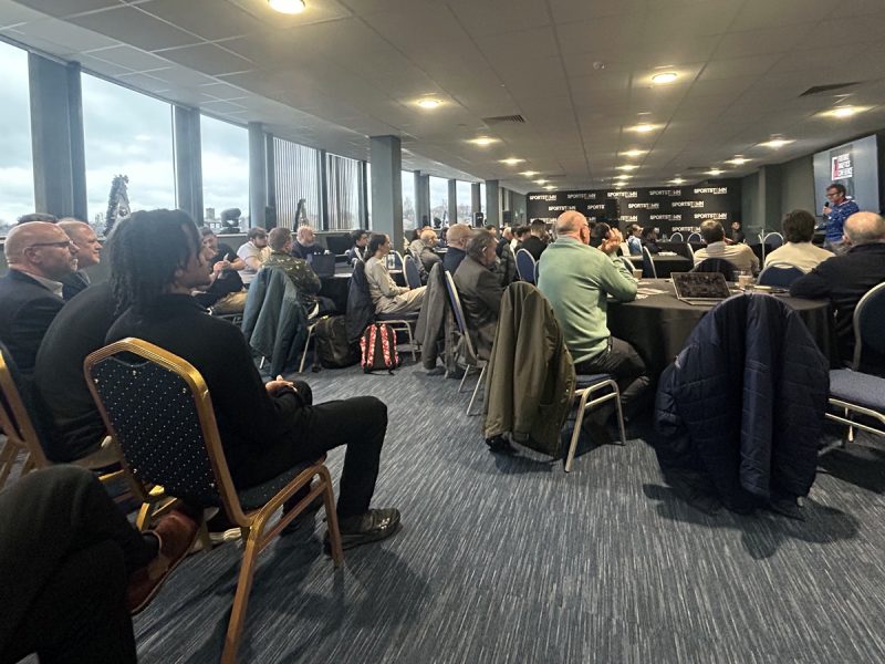 Attendees seated at Football Analytics Conference in meeting room with windows.