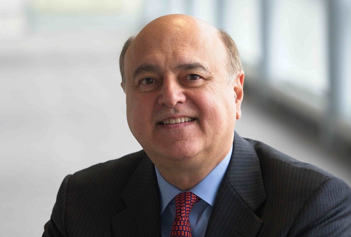 Executive seated indoors, dressed in formal business attire