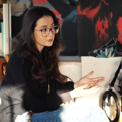 Woman with dark hair, glasses and black top pictured in a studio